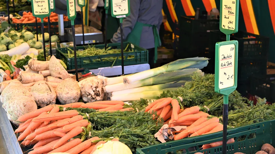 Frisches Gemüse auf einem Marktstand: Karotten, Lauch, Sellerie und Rote Bete in einer einladenden Anordnung.