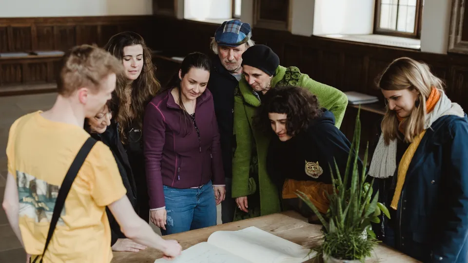 Eine Gruppe interessierter Besucher studiert gemeinsam einen alten Stadtplan in einem historischen Gebäude.