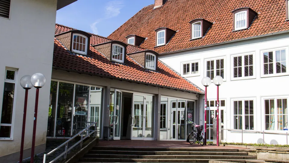 Eingang zum Haus der Jugend in Osnabrück mit rotem Ziegeldach und großen Fenstern im Tageslicht.
