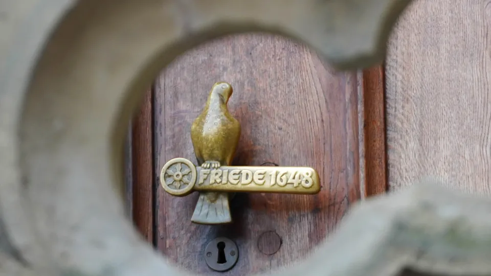 Türklinke am historischen Rathaus von Osnabrück. Eine goldene Taube sitzt auf einer Symbolstange.