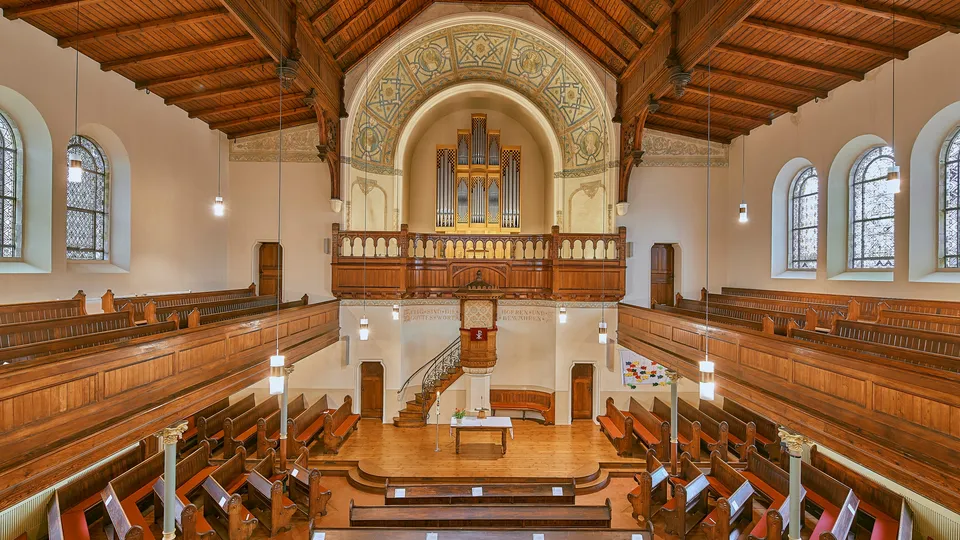 Innenansicht einer historischen Kirche mit hölzerner Empore, prachtvoller Orgel und alten Kirchenbänken.